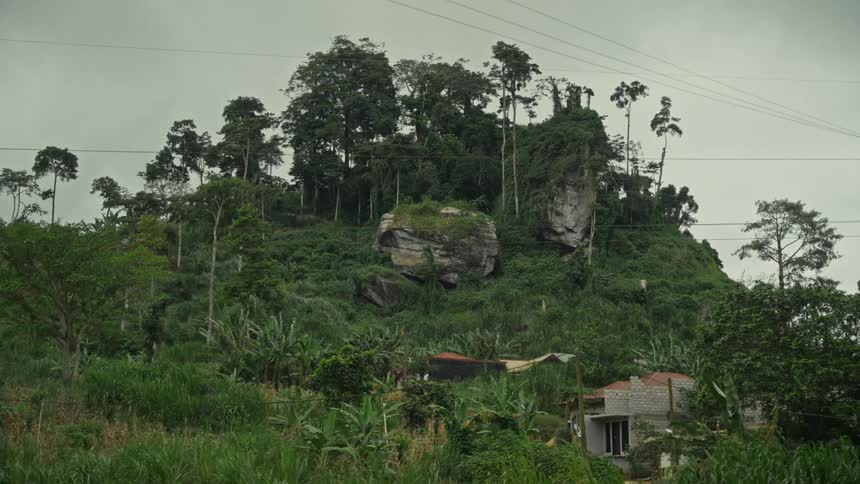 Person walks past a sign near a rural building standing at the base of a hill on an overcast day