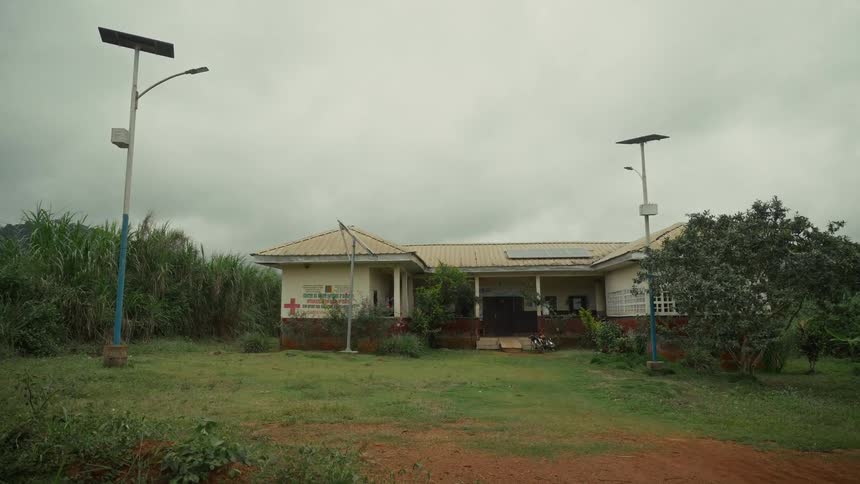 Isolated health post building surrounded by vegetation under a cloudy sky