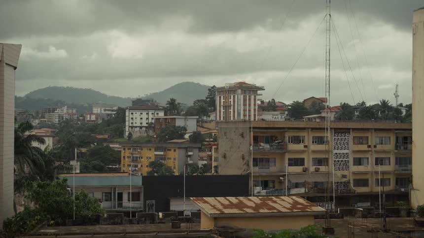 Urban buildings blend with trees and hills in the background under a gray sky