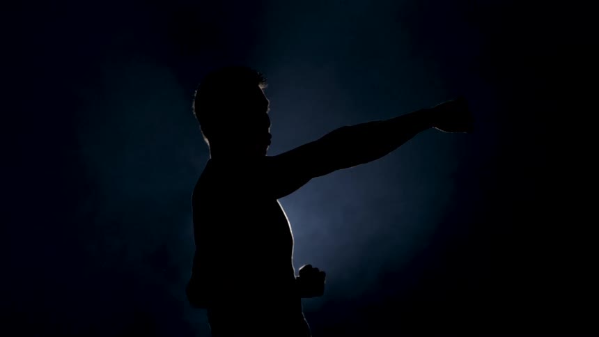 A silhouetted male figure with short hair pointing to the right against a dark blue foggy background
