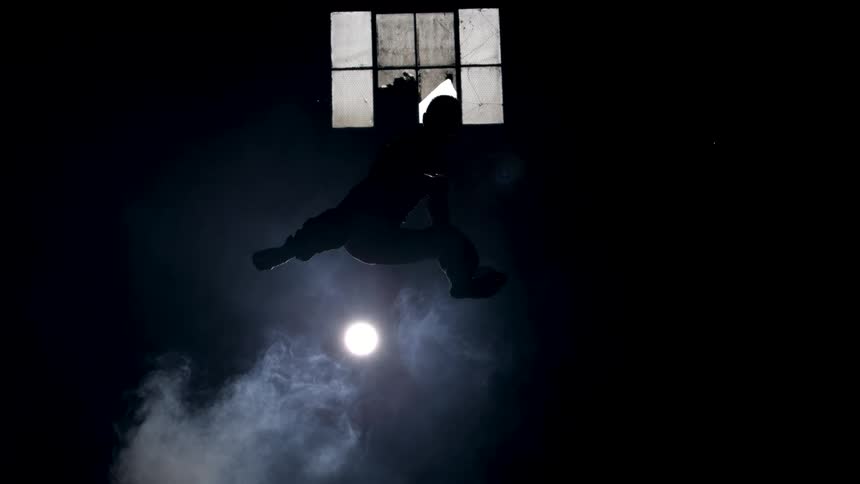 A man is doing martial arts in a dark smoky room