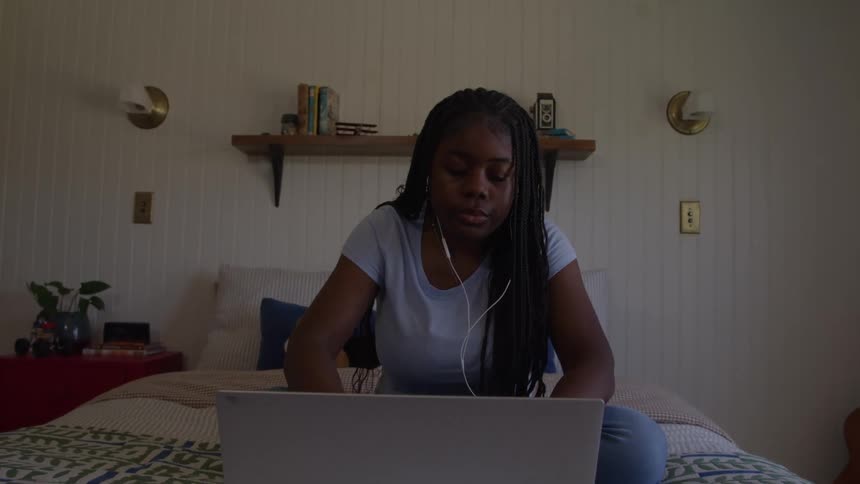 The girl opens her laptop in bed