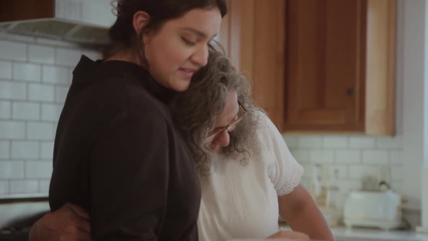 Two women share a moment of closeness in the kitchen