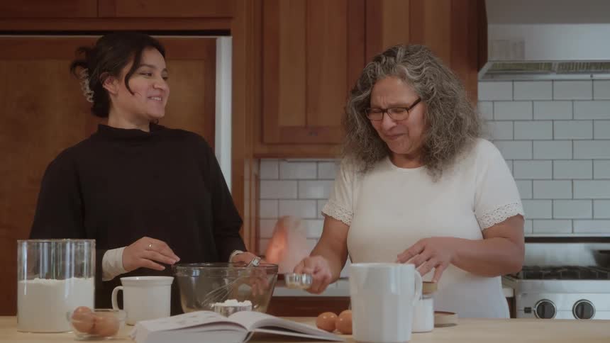 A mother and daughter measure baking ingredients in the kitchen