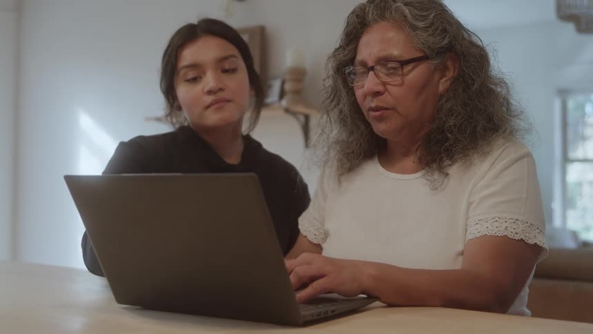 The teenager is pointing at the laptop screen