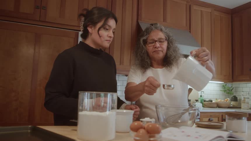 A mother and daughter are cooking in the kitchen