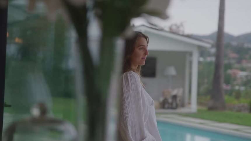 A woman looking out the window to her backyard