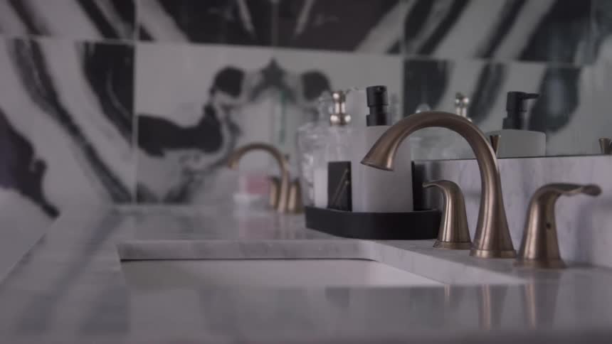 A bathroom with a golden faucet on the sink several soap dishes on the countertop and a mirror on the wall at midday