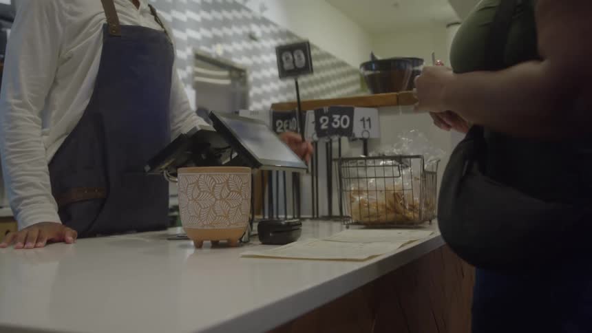 A woman pays for her order at a counter and the male worker hands her a number sign