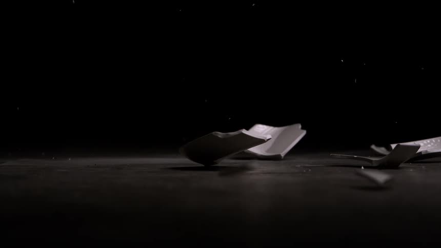 A dish falls down onto the floor and breaks into many pieces