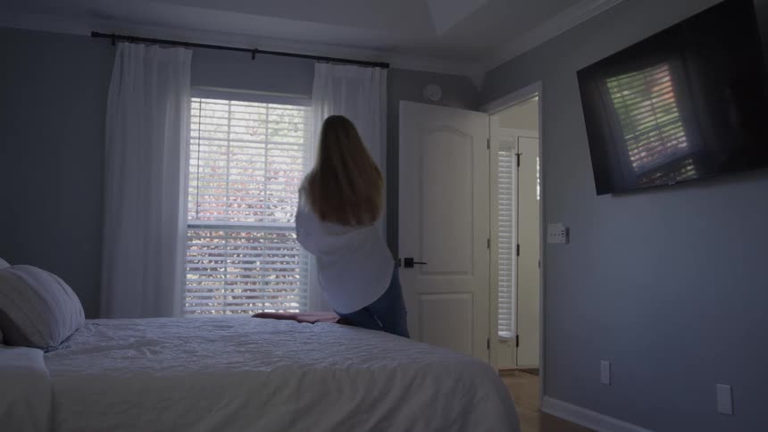 Woman lies on the bed watching television in a bright bedroom