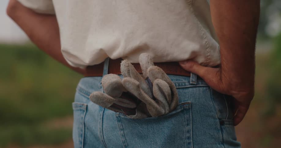 Man standing with his hands on hips and work gloves in the back pocket of his jeans