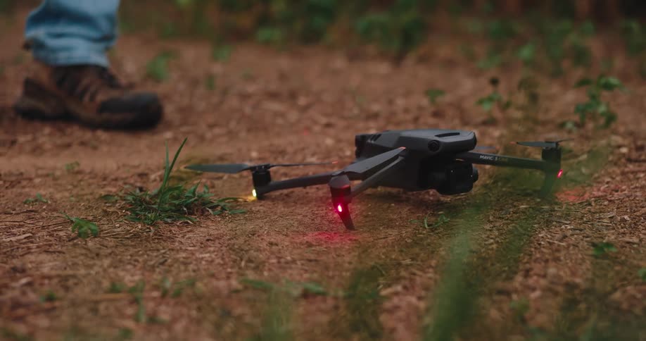 Man holds a drone with lights on and sets it on the ground