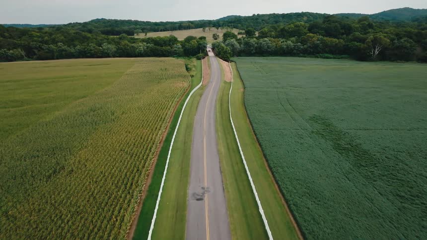 Aerial of cars driving down a rural highway in farm country