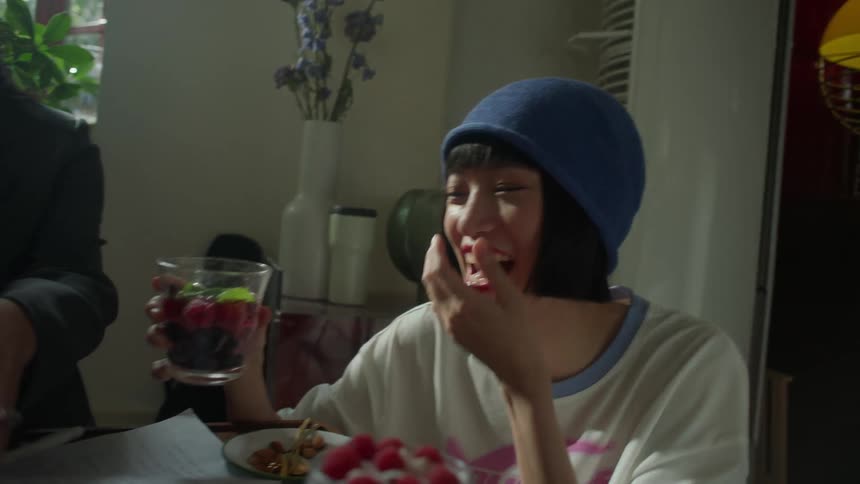 Two women laugh and enjoy a light moment at an indoor table with berries and mint