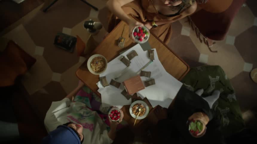 Three friends toast with bowls of mixed berries over a table in a cafe