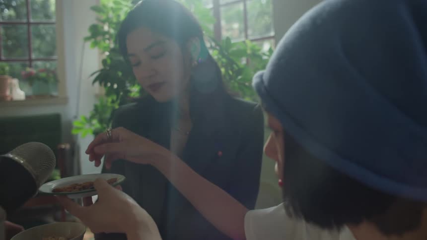 Female friends smile as one of them drops food into a plate near a microphone