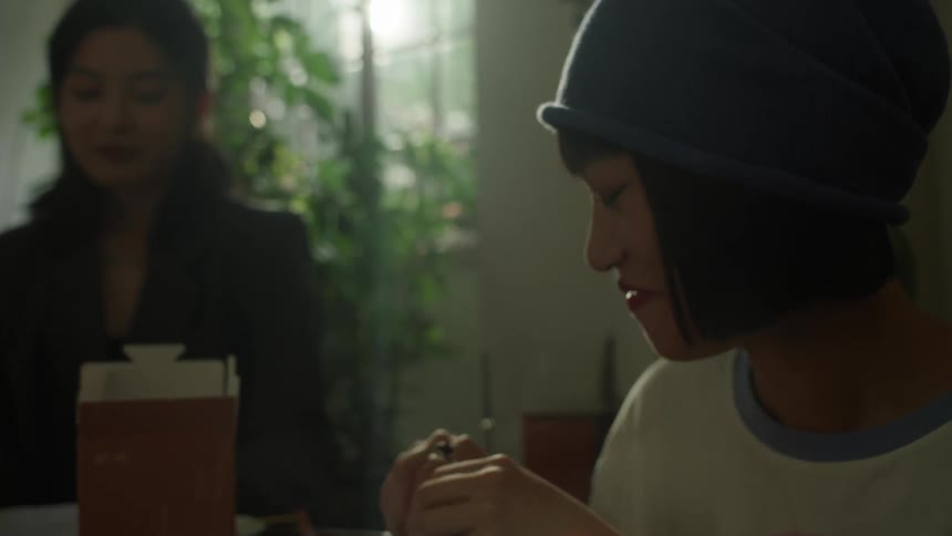 A man gets food from a takeout box while a woman watches