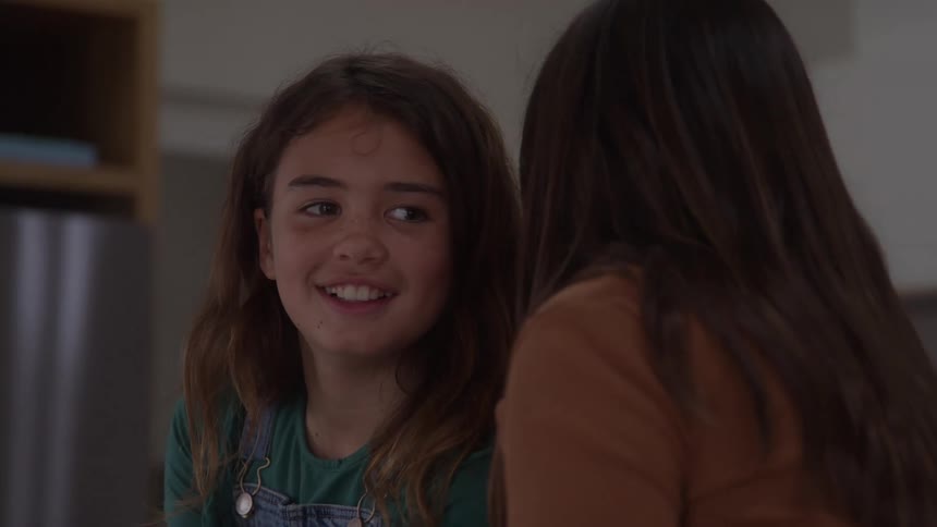Girl smiles while her friend whispers into her ear