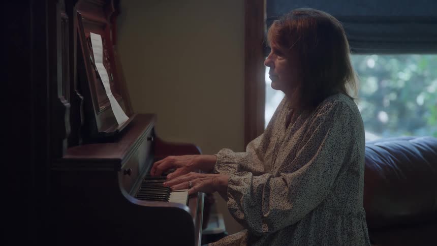 Woman plays the piano while reading the sheet music on the stand