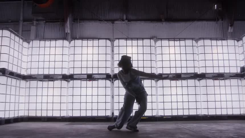 A person dancing indoors with several bright light blocks behind them