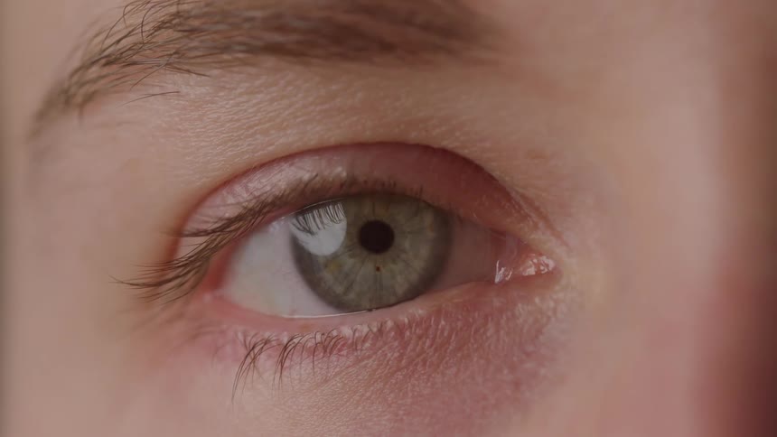A persons green eye slowly opens to look forward
