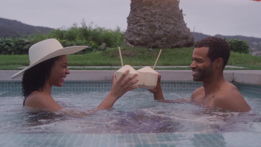 A man and woman drinking cocktails while swimming