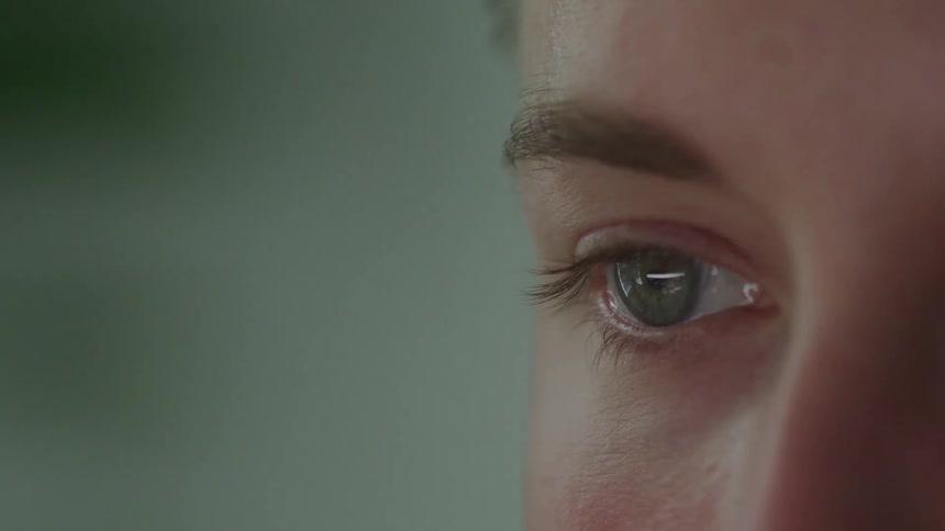 The eye of a person with a green iris is reflecting an image and the person is not blinking