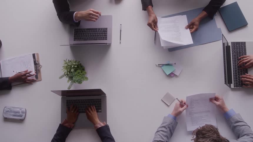 Team meeting with laptops and documents spread across the table