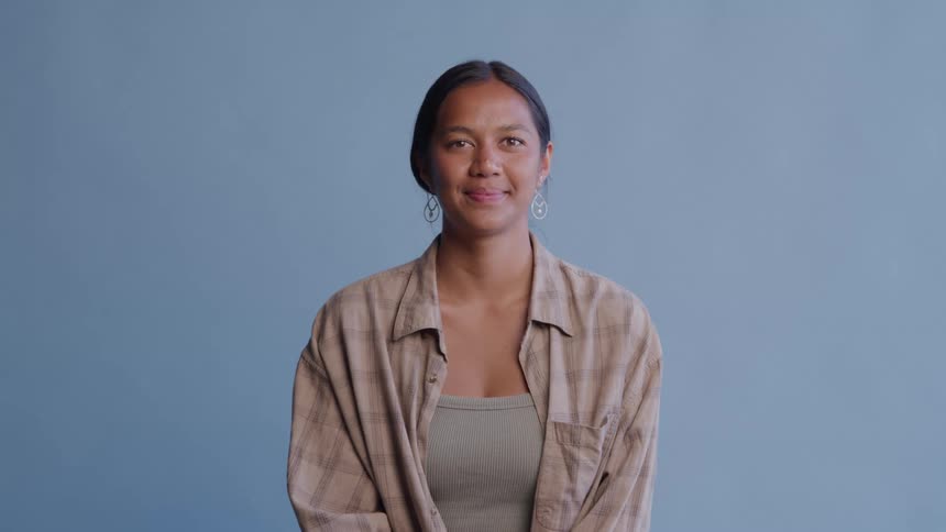 Woman smiles gently while seated against a blue background