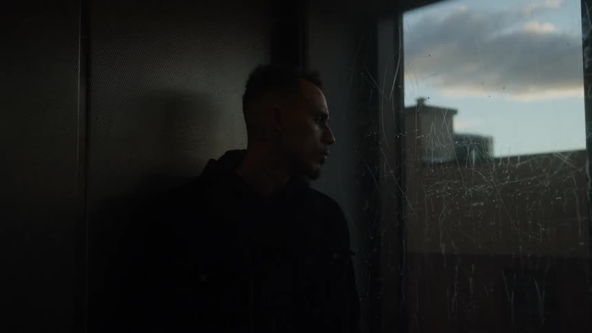 Man in an elevator looks to the side as sunset light comes through the window