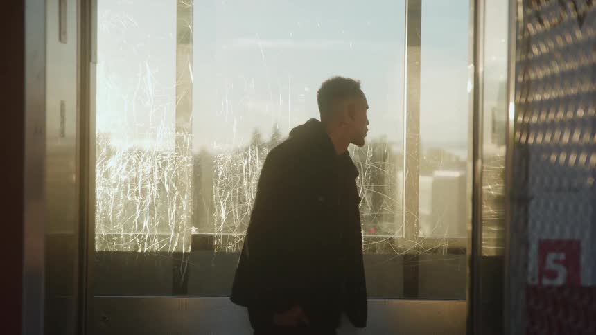 Man enters an elevator illuminated by the light of the setting sun