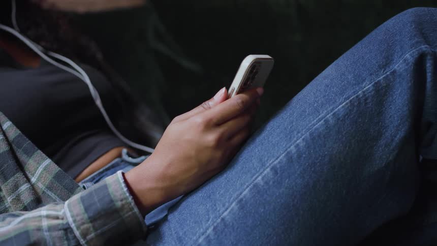 Woman scrolls on her smartphone while listening to music on it
