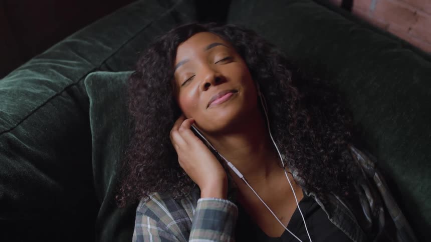 Woman sings with her eyes closed while listening to and singing along to music through headphones