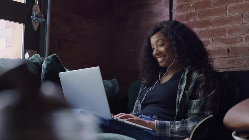 Woman smiles and waves during a video call on her laptop