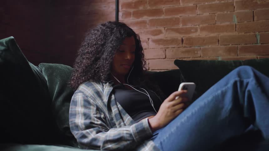 Woman sitting on the couch listening to her music player