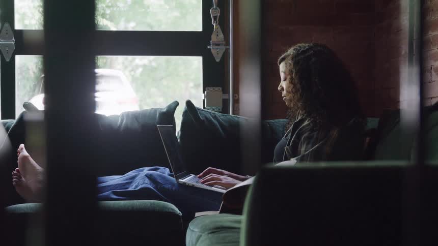 Woman sitting on the couch typing on a laptop computer