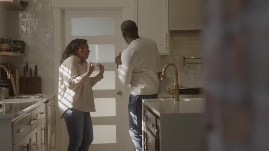 Couple dances and chats energetically in the sunlit kitchen
