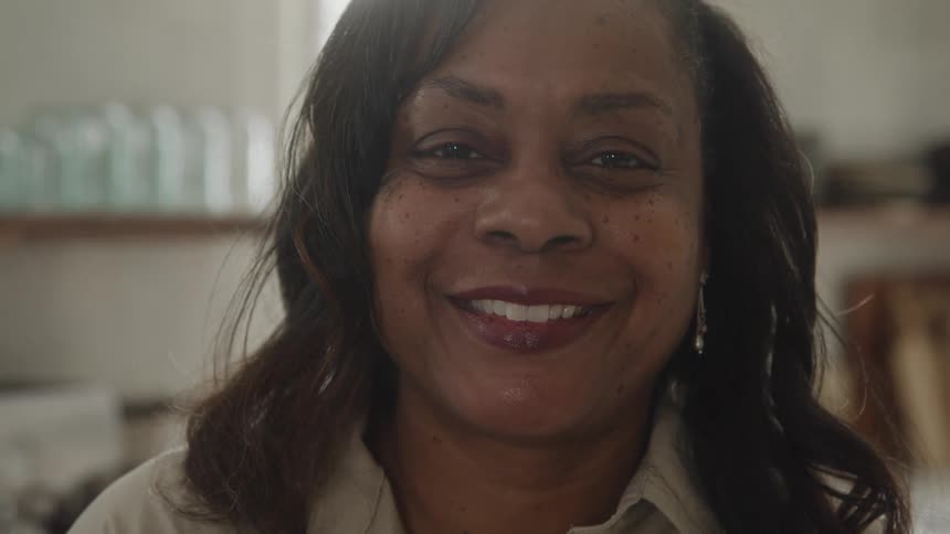 A woman slowly turns her head and smiles for the camera