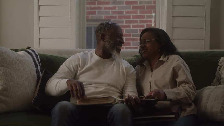 Couple sitting on the couch looks through an open photo album together