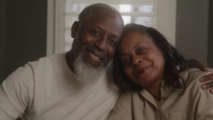 Older couple sitting together near a window look into each others eyes before leaning against each other