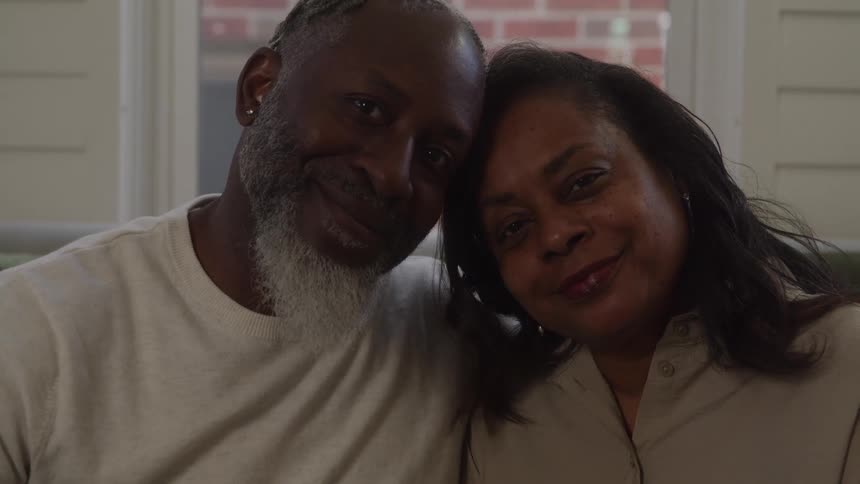 An older couple shares a tender moment looking at each other lovingly before turning to smile warmly