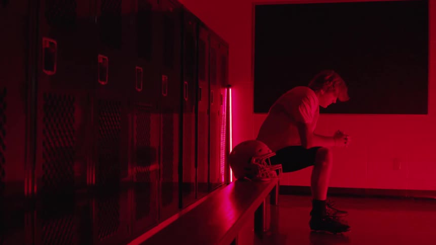 Athlete sits in the locker room lit by red light