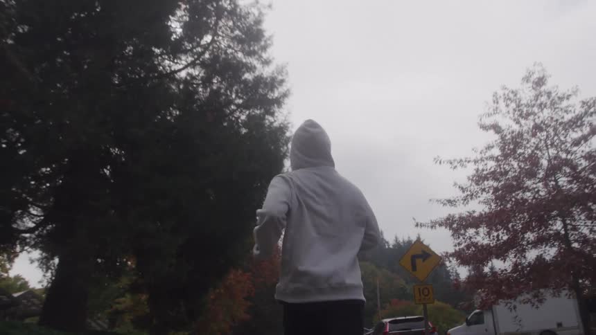 Man wearing a hoodie runs down a neighborhood street