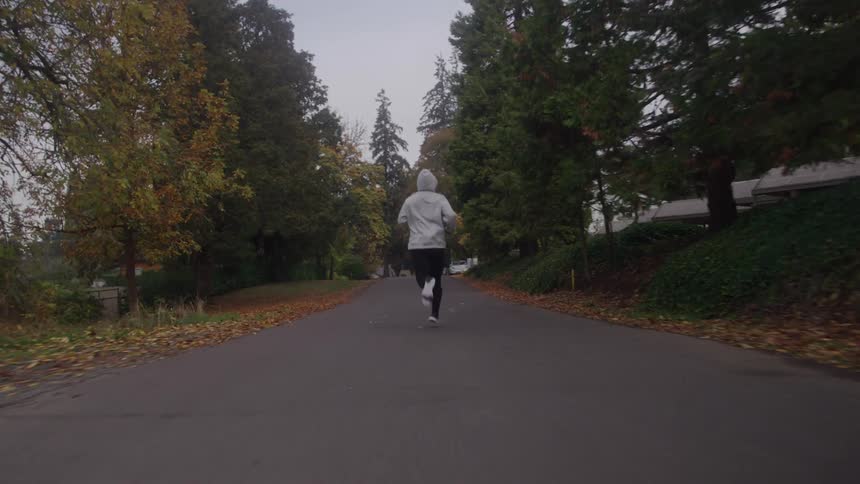 Jogger runs along a road past houses on an autumn day