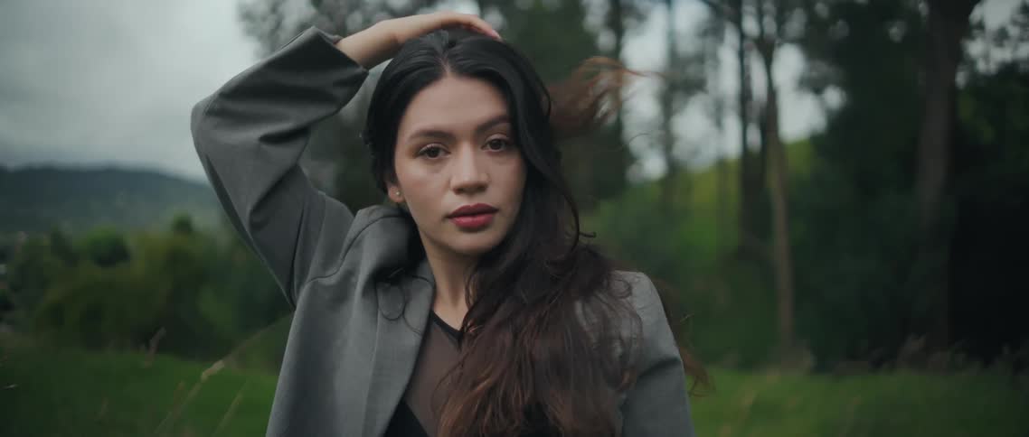 Woman places her arm behind her head while holding a direct gaze in the field