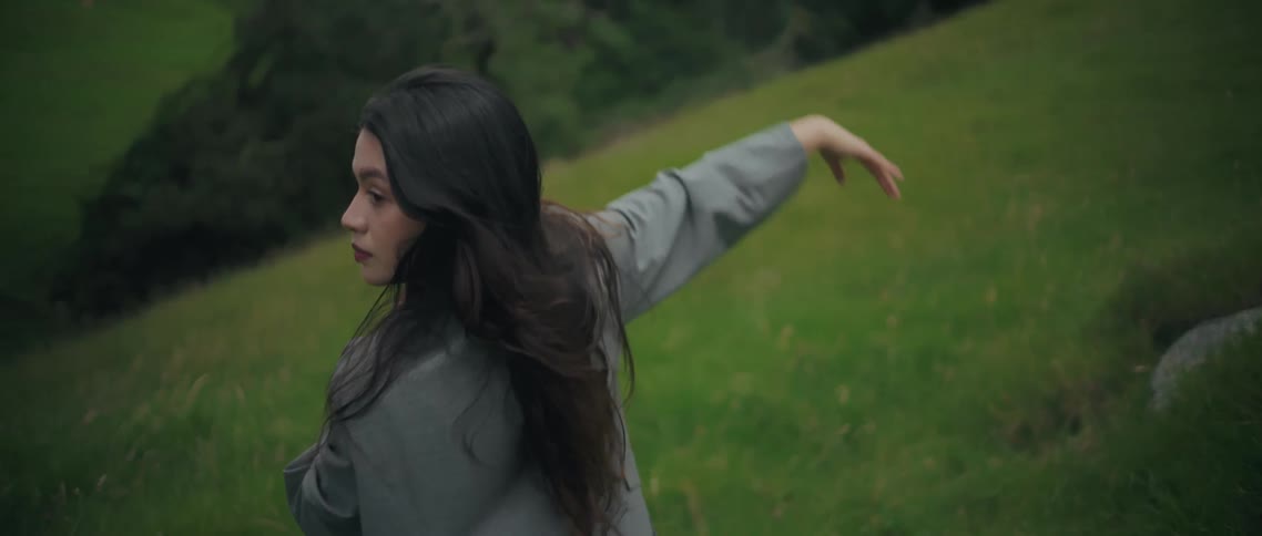 A woman dancing outdoors in a grassy field