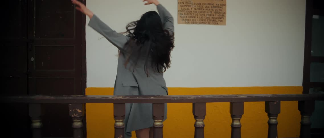 Ballet dancer dances incorporating the rail outside a building during the daytime