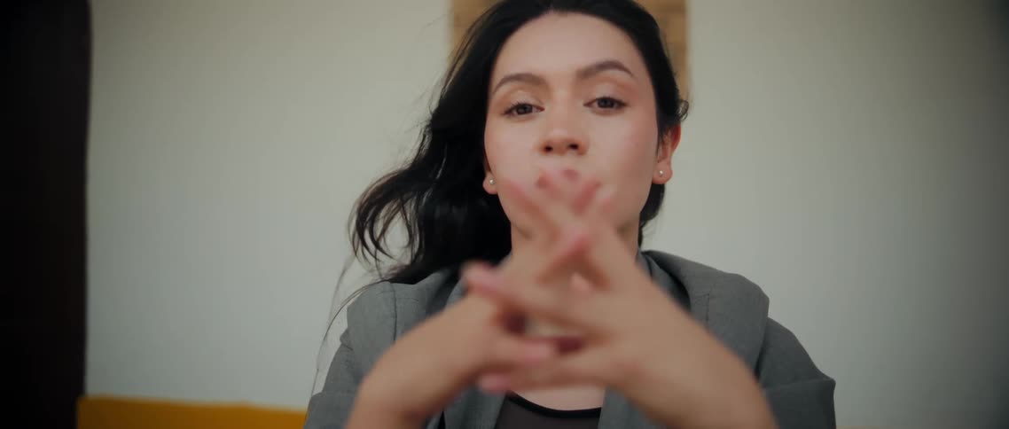 Woman interlaces her fingers in front of her face while holding a calm