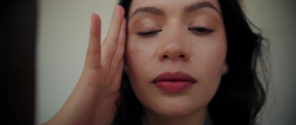 Woman touches her face with her hand while holding a soft closeup gaze